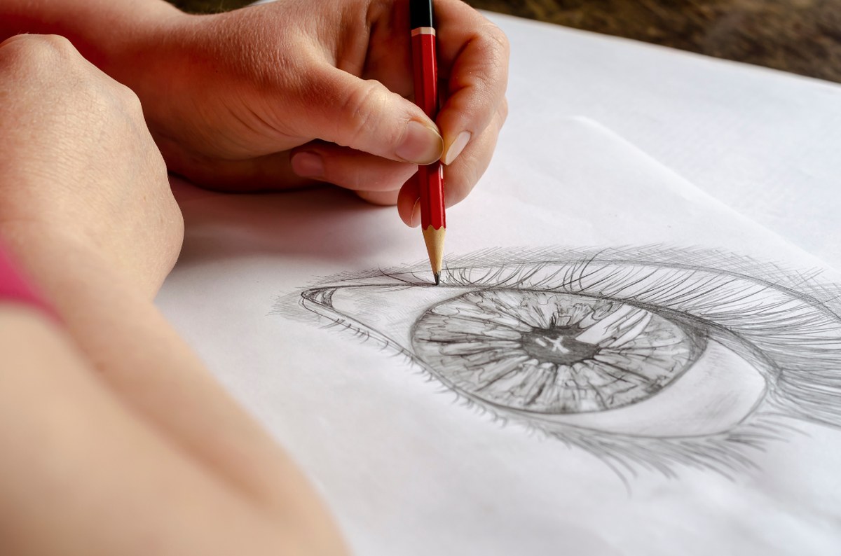 Student sketching a detailed pencil drawing of an eye
